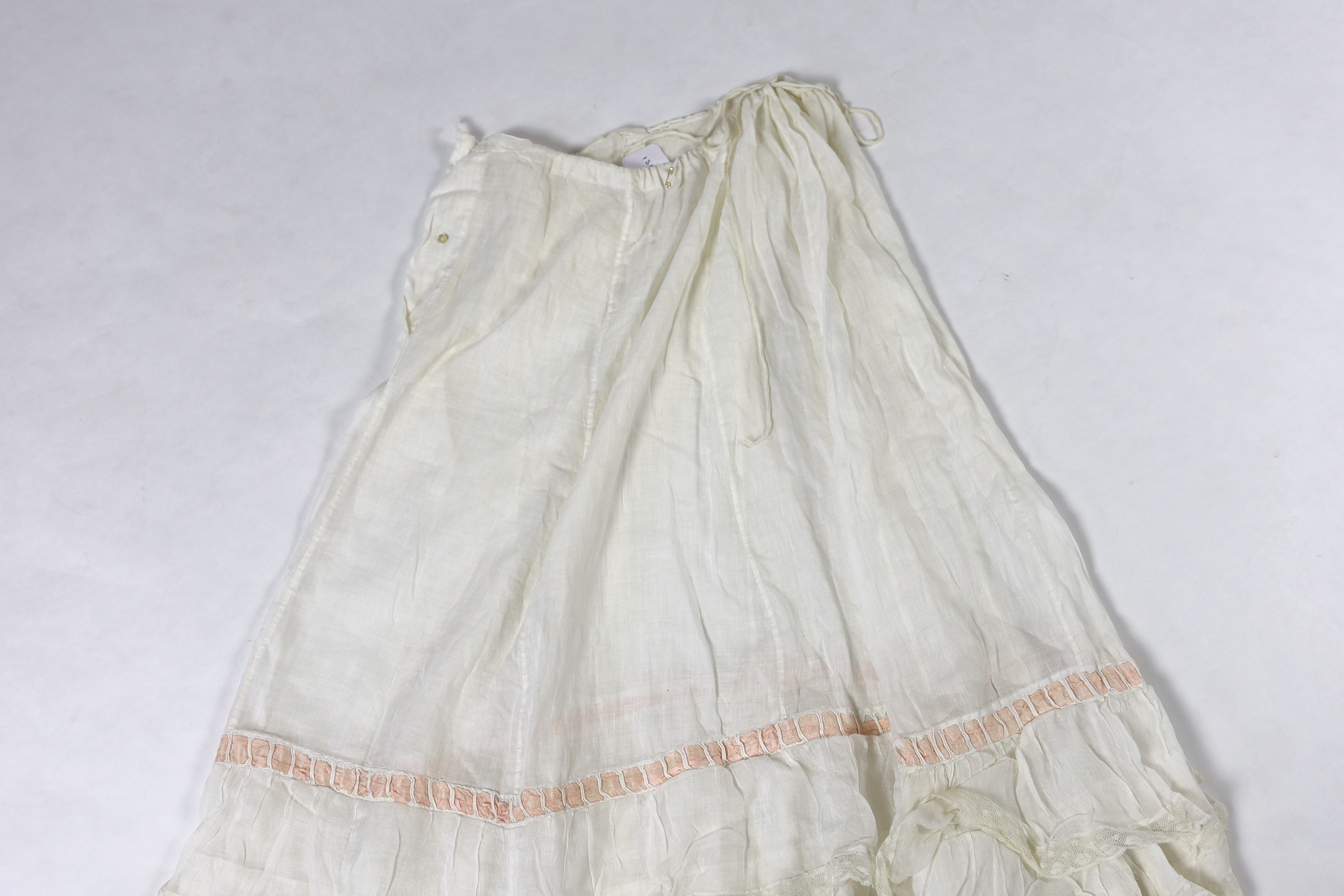 Three Victorian white worked petticoats; one two tiered, one lace trimmed with ribboning, the third worked with cutwork border, all approx. 94cm long